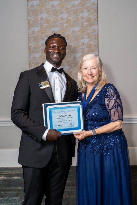 TreVaughn Ellis accepts his scholarship certificate from Bonnie Toth, a member of Divers Alert Network, during the NOGI Awards banquet Nov. 12.